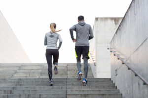 An active man and woman running up the stairs to represent exercise and maintaining good health
