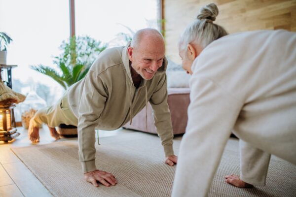 older couple doing yoga indoors in the winter to take care of their vein health and varicose veins