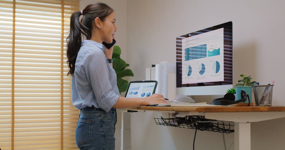 Electric,Adjustable,Standing,Desk,In,Small,Office,Workspace,For,Pc woman working at a standing desk